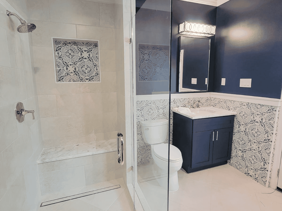 Modern bathroom with walk-in shower and stylish vanity. Bathroom with walk-in shower, toilet, and navy blue vanity with decorative wall tiles.