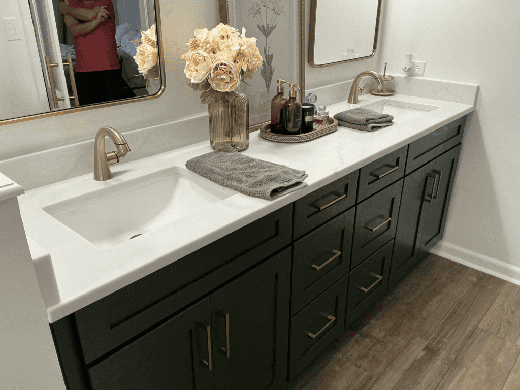 Bathroom vanity with double sinks, gold hardware, and floral decor.