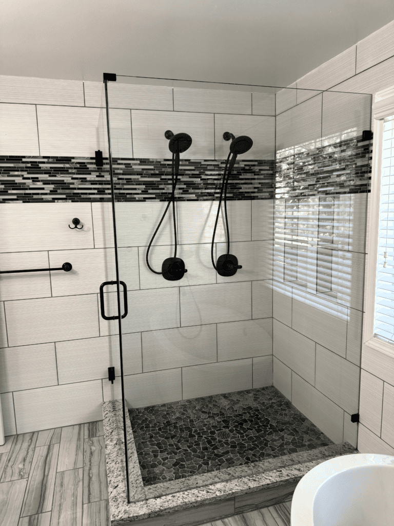 Walk-in shower with dual black showerheads and glass door.