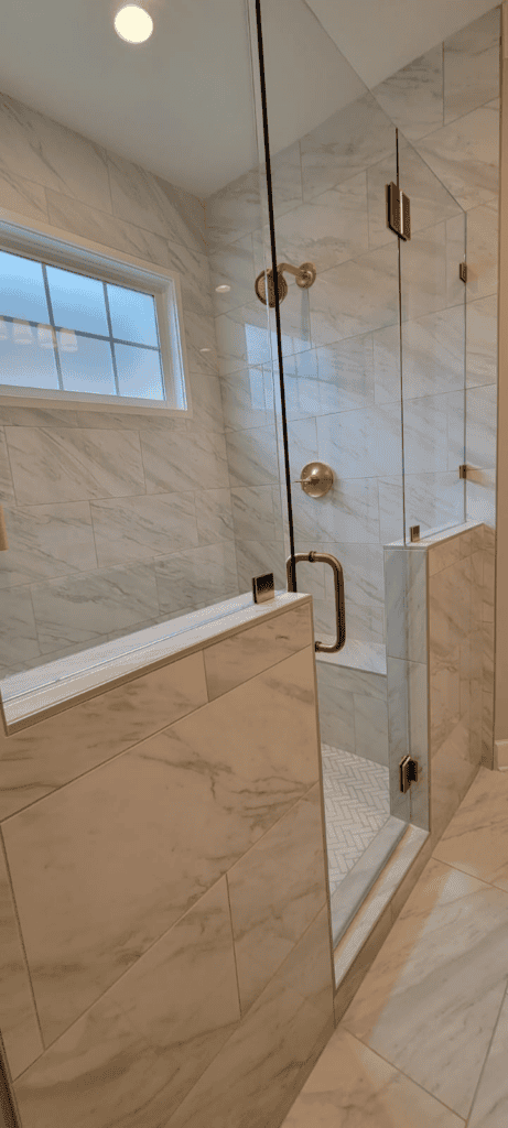 Elegant glass shower with gold fixtures in a luxurious bathroom setting.