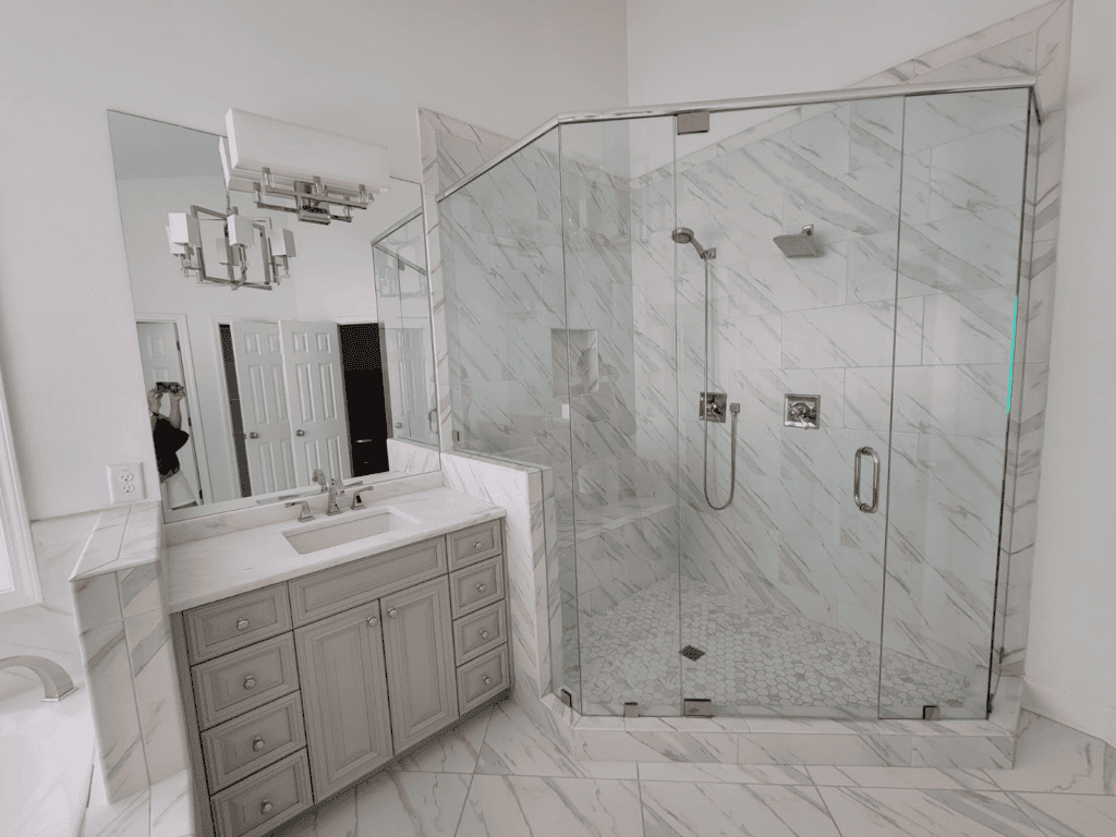 Modern glass shower enclosure with marble tiles in a renovated bathroom.