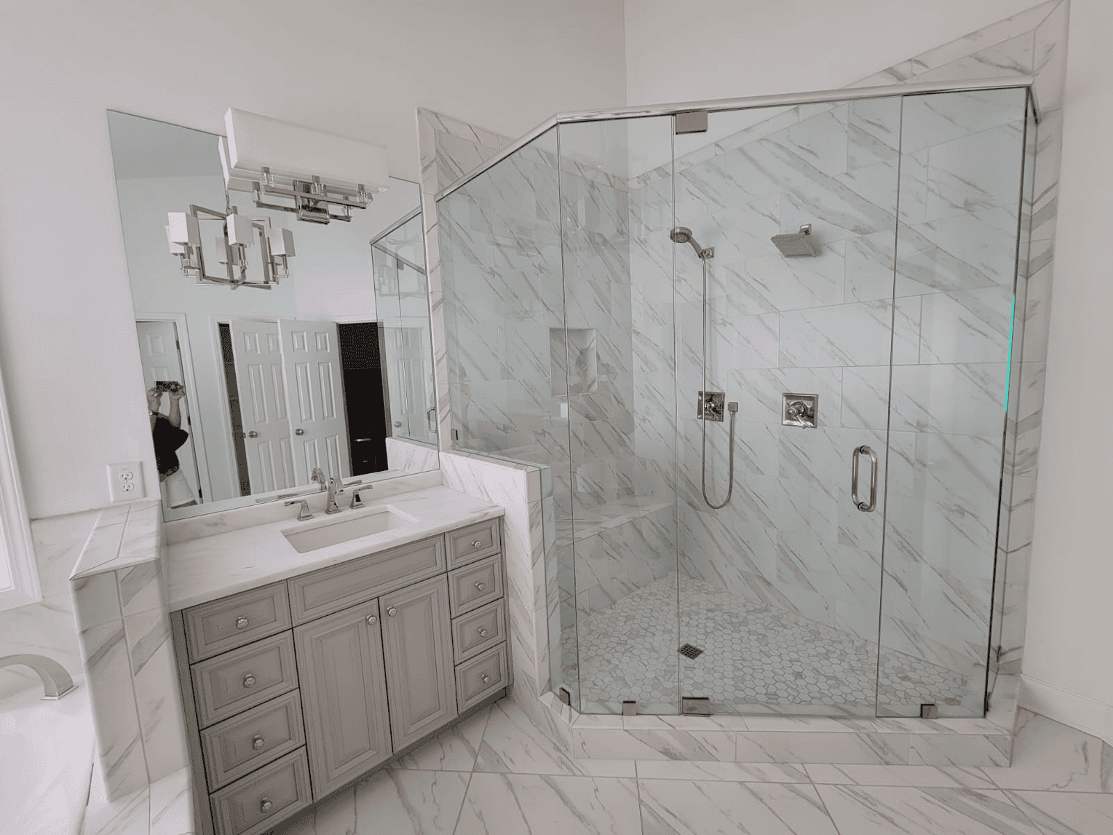 Modern glass shower enclosure with marble tiles in a renovated bathroom.