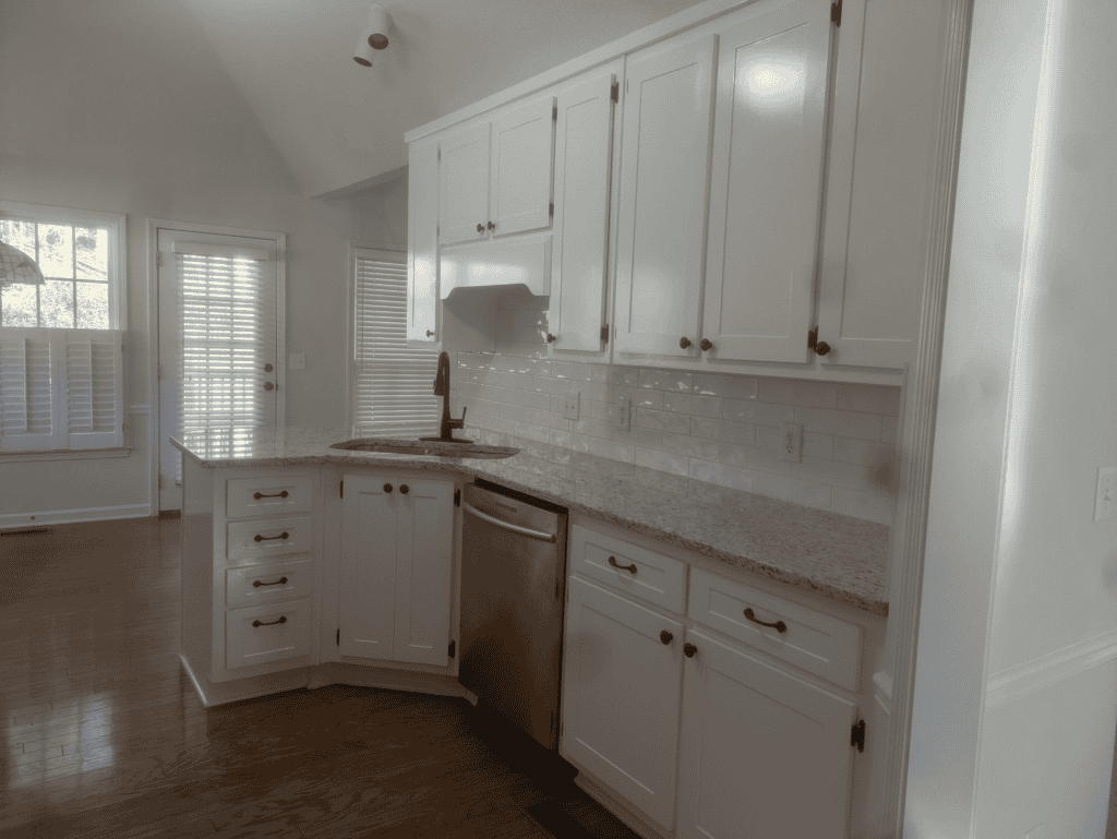 Modern white kitchen cabinets with granite countertops and stainless steel appliances.