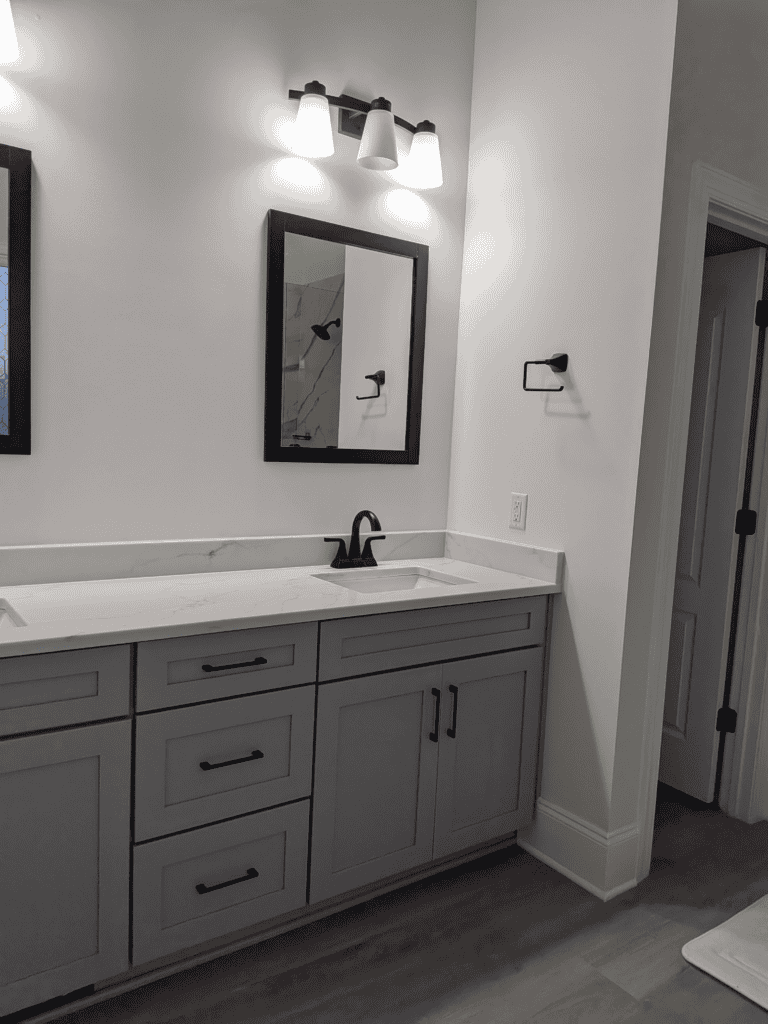 Bathroom vanity with mirror, lighting, and sleek gray cabinetry.