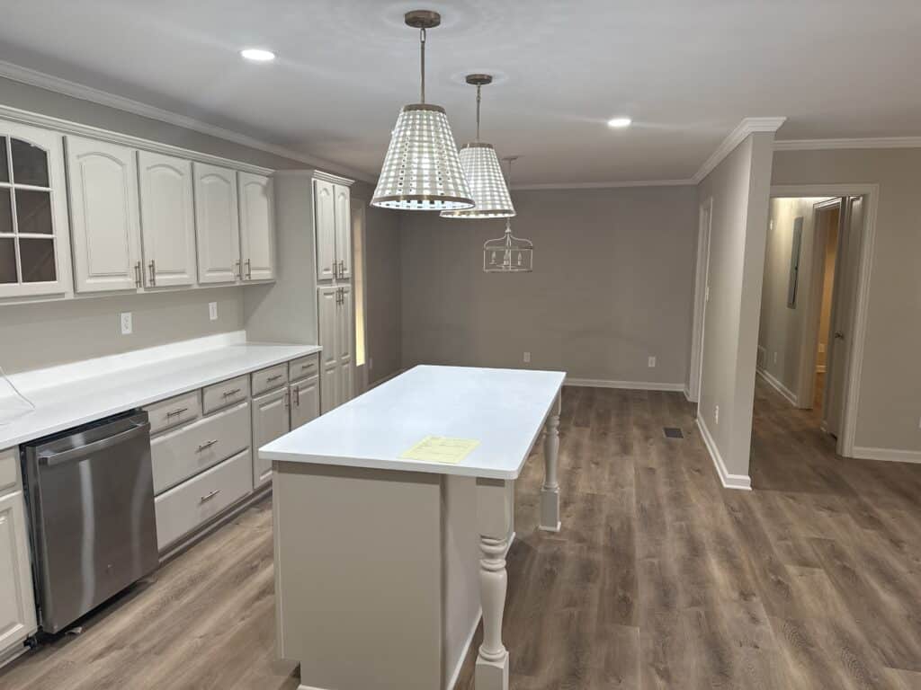 Bright, modern kitchen with white cabinets, island, and pendant lighting.